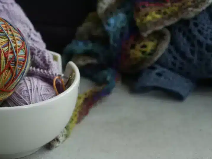 Een detail van een wolpot van keramiek met daarin paarse en gekleurde wol