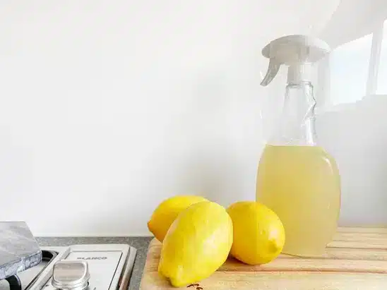 een spuitfles met vloeistof en citroenen op een keukenaanrecht
