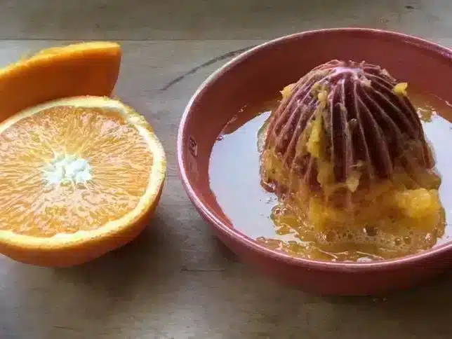 Een roze citruspers gemaakt klei met een sinaasappel ernaast