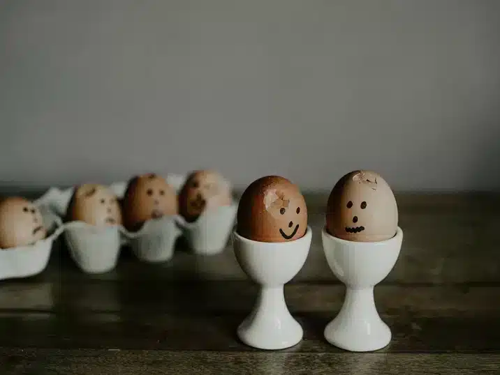 Twee eierdopjes met daarin eitjes waarop een gezichtje werd getekend