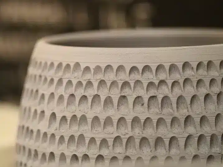 Een detail van een pot uit klei waarvan de wanden bewerkt zijn met de techniek kerven