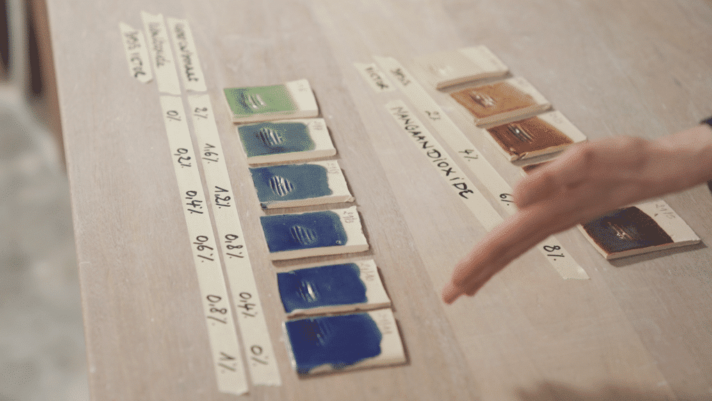 Testplaatsjes van geglazuurde keramiek in verschillende kleuren met percentages van de samenstelling
