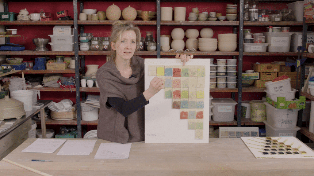 Cursist docent Aster Caemaert in haar atelier met testplaatjes geglazuurde keramiek volgens de multimengmethode