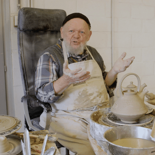 Cursist docent Fernand Everaert in zijn atelier met een theepot op de draaischijf