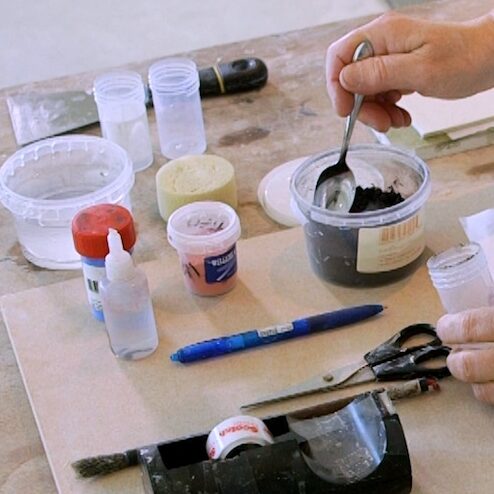 Cursist docent Anima Roos schept pigmentpoeder in een potje voor een decoratietechniek op keramiek