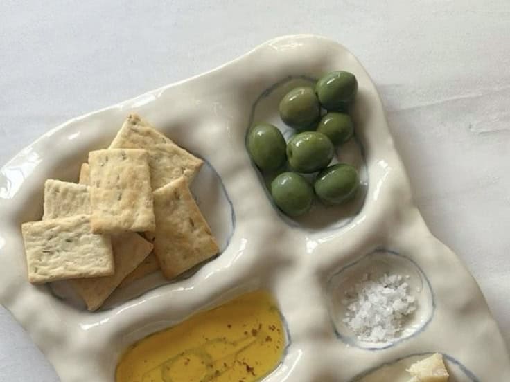 De tapasschaal in keramiek gebroken wit compartimenten olijven chips